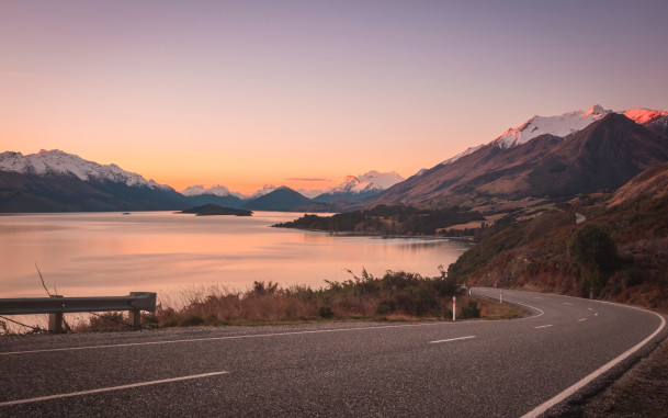 Bennetts Bluff at sunset with Lake Wakatipu and mountains in the background under a pink and orange sky