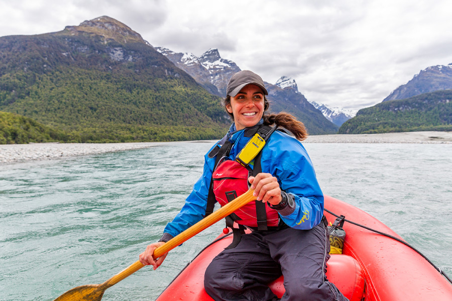 Funyak tour guide in inflatable kayak surrounded by mountains and native forest in Mount Aspiring National Park.