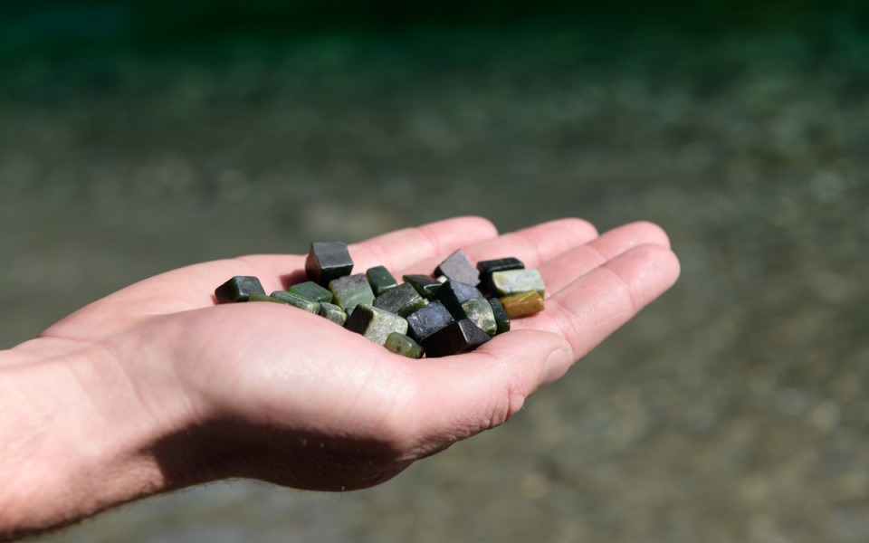 Outstretched hand holding several pounamu (greenstone) pieces