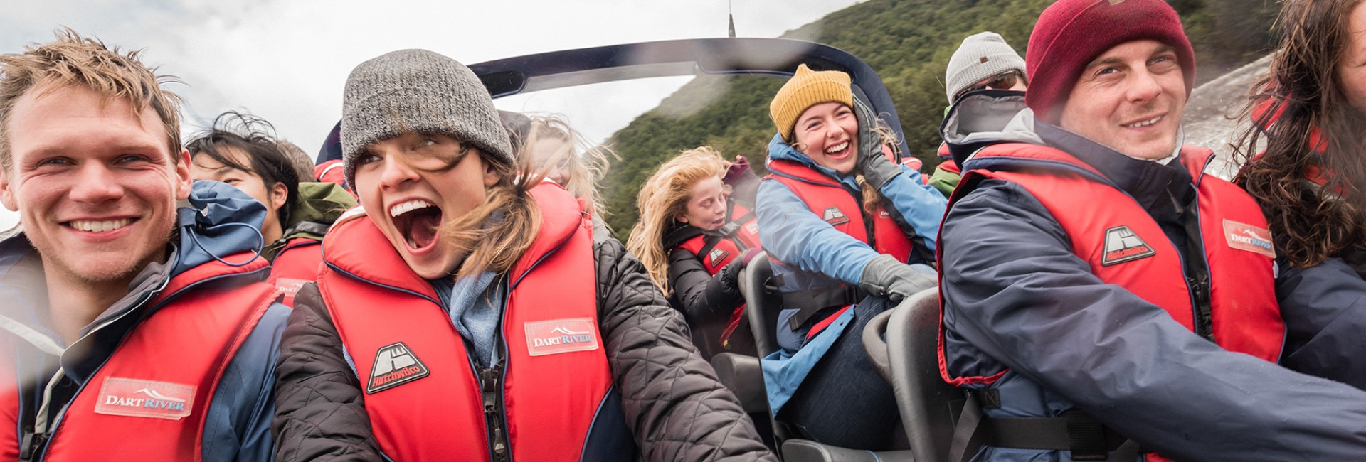 Close-up of visitors on a jet boat as it speeds down the river, with excited, smiling faces.